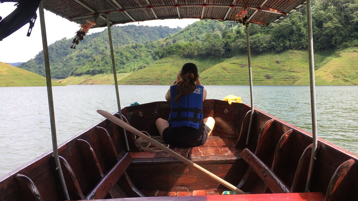 Long tail boat ride through the vast surface of water inside the dam with cool breeze air flowing through your hair